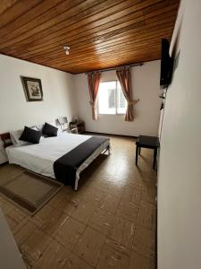 亚美尼亚Hotel Alpino的一间卧室设有一张带木制天花板的大床