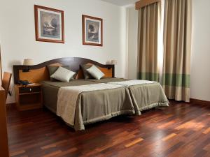 富尔纳斯淡水河谷豪园酒店的一间卧室配有一张床,铺有木地板