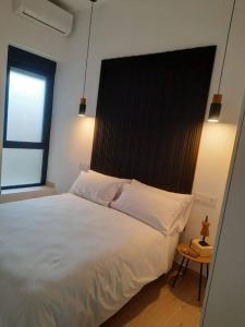 萨莫拉Colon 13的一间卧室配有一张白色大床和黑色床头板