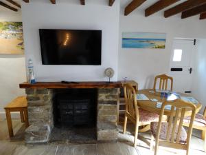 布里德波特Staddlestones Cottage的客厅设有壁炉和墙上的电视