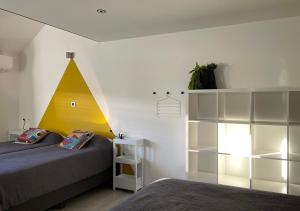 Sint-Martens-VoerenArcaden的卧室配有一张床,墙上有一个黄色金字塔