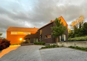 Sint-Martens-VoerenArcaden的一座带橙色屋顶和车道的房子