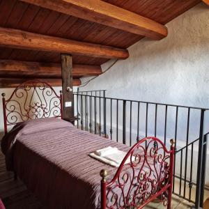 CastelnuovoIl pozzo dei desideri的一张红色的床,位于一个拥有木制天花板的房间