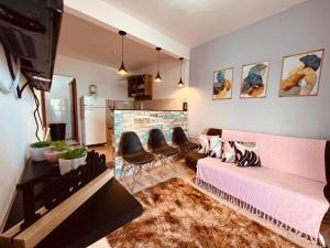 圣佩德罗-达阿尔德亚Apto Aconchego da Aldeia próximo ao centro e praias的客厅配有粉红色的沙发和椅子