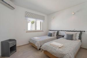 韦尔都勒博Villa Isabel的一间白色卧室,配有两张床和窗户