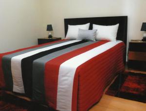 BesteirosCasa Quelhas的一张带红色白色和黑色毯子的大床