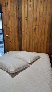 托雷斯Lindo Residencial na Praia Itapeva Torres的一张铺有白色床单和木墙的床