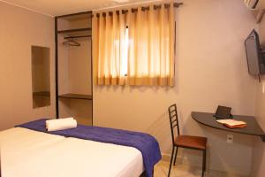 巴西利亚Hotel Montana Aeroporto的客房设有一张床、一张桌子和一张桌子。