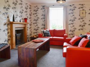 BelladrumKennels Cottage - Beaufort Estate的客厅设有红色的沙发和壁炉