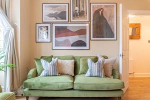 伦敦Dahomey Home - Streatham - London的客厅里一张绿色沙发,墙上挂着照片