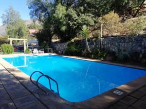 圣何塞德迈波Cabañas Lomas del Manzano的一座大型蓝色游泳池,毗邻石墙