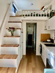 NethercoteTiny Nerak的一间厨房,厨房内有白色的橱柜和楼梯,位于一个小房子里