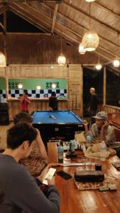 TomohonRimba eco Resort的一群人坐在一张桌子上,桌边摆放着台球桌