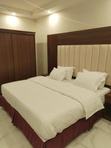奈季兰هوتيل نجران للشقق الفندقية的卧室配有一张白色大床和木制床头板