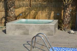 拉斯阿尔卡麦Dar 66 Pool Villa with Jacuzzi的木墙旁混凝土浴缸中的游泳池