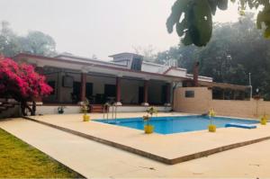 塔拉Maharaja Kothi Resort, Bandhavgarh的一座房子前面设有游泳池