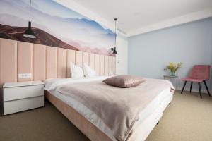 德瓦Vila Sarisa的卧室配有一张大床,墙上挂有绘画作品