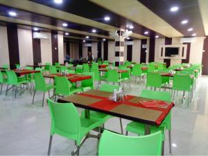 王舍城Hotel Glory Grand, Rajgir的用餐室配有绿色的桌椅
