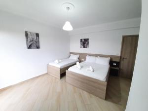 卡萨米尔Soare的配有白色墙壁和木地板的客房内的两张床