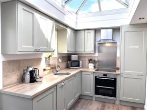 水上伯顿Ardenlea的厨房配有白色橱柜和天窗。