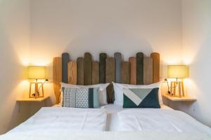 塞布鲁克QC Hotel Quartier Chiemsee的一间卧室配有一张带两盏灯的大型白色床。
