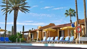 英格兰海滩Bungalows Los Almendros - Exclusive Vacation Club的一个带椅子和棕榈树的度假村和游泳池