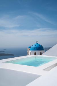 易莫洛林Cilon Suites Santorini的一座蓝色屋顶游泳池和一座教堂