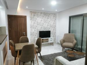 哈马马特Sublime appartement le Palace Hammamet Nord Mrezga的客厅配有桌椅和电视。