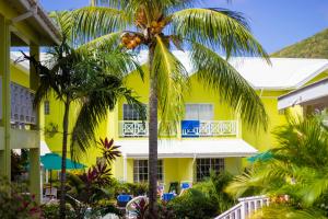 格罗斯岛海湾花园酒店的一座棕榈树的黄色建筑