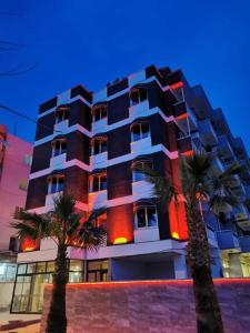 库萨达斯Akman Hotel的一座高大的建筑,前面有棕榈树