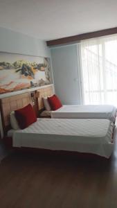 库萨达斯Akman Hotel的卧室内的两张床和红色枕头