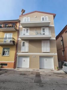 雷卡纳蒂港Appartamenti nuovi in centro a Porto Recanati Riviera del Conero的一座高高的建筑,有四扇白色的车库门