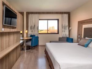 大坎普大坎普诺富特坎酒店的酒店客房设有床、桌子和窗户。