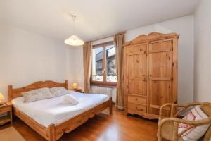 夏蒙尼-勃朗峰Résidence Alpes 2的一间卧室配有一张床和一个木制橱柜
