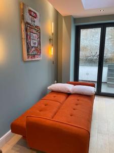 伦敦1 Bed Garden Flat Finsbury Park的窗户客房内的大橙色沙发