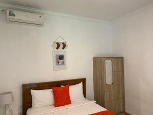 珀尼达岛Umah Putih的一间卧室配有带橙色和白色枕头的床