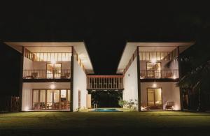坦加拉Sati Villa Rekawa Beach Sri Lanka的一座白色的大建筑,晚上有窗户
