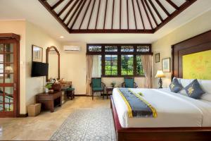 勒吉安Royal Tunjung Hotel & Villa Legian - CHSE Certified的一间卧室配有一张床、一张书桌和一台电视