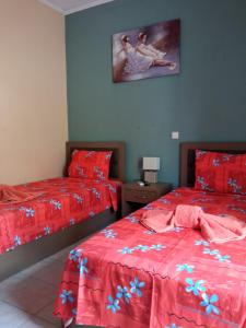 卡兰巴卡Teo's House 2的一间卧室配有两张带红色床单的床,墙上挂着一张照片