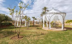 马拉喀什Maison Daouia的花园设有凉亭、桌子和树木
