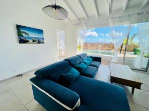 圣吕斯Villa Amaryllis luxueuse,piscine,vue mer,plage的客厅设有蓝色的沙发和大窗户