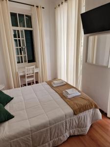 丰沙尔Hospedaria Pôr do Sol的一间卧室配有一张大床和两条毛巾