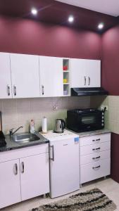 松博尔Apartman Maja的厨房配有白色橱柜、水槽和微波炉