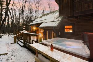 奥克兰Jamesons Cabin! 8 Minutes to Wisp, HotTub, FirePit, Pets, EV Chgr的雪中房子边的热水浴池