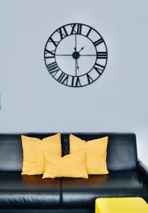 加尔达湖滨RivApartmentsDowntowN Urban的一张带黄色枕头的黑色沙发,墙上挂着一个钟