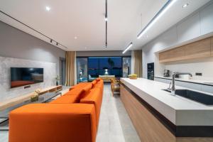 锡德Villa Milo的一间带橙色沙发的客厅和一间厨房