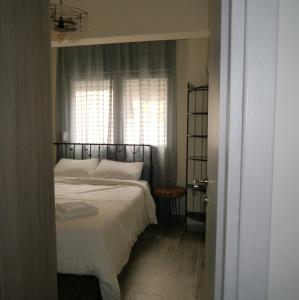 塞萨洛尼基Cozy & Stylish Eastside Apt.的一间卧室配有一张带白色床单的床和一扇窗户。