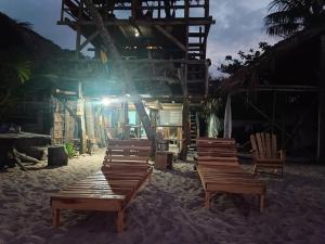 GuachacaBob Marley Beach的一组木椅,坐在建筑物前的沙子里