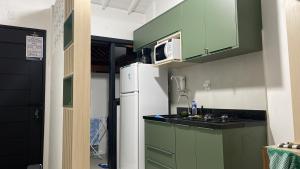 马塔迪圣若昂Apartamento Praia do Forte的厨房配有绿色橱柜和白色冰箱
