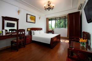 河内Hanoi Moonlight Hotel的一间卧室配有一张床、一张书桌和一面镜子